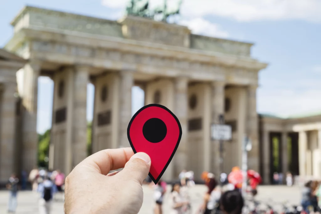 Eine Hand h&auml;lt ein Standort-Icon vor dem Brandenburger Tor f&uuml;r die Pflegedienst Lux Standorte Berlin