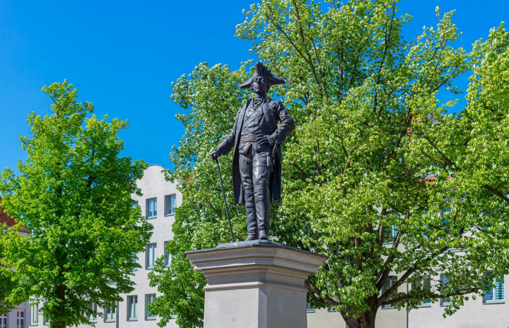 Das Friedrich-Denkmal vor grünen Bäumen für die Pflegeberatung Berlin-Friedrichshagen bei strahlend blauem Himmel